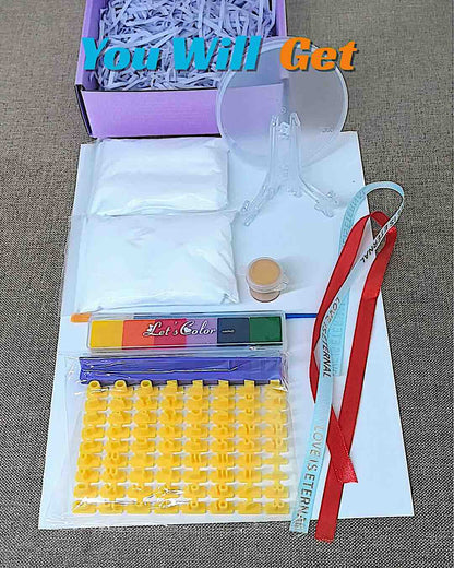 DIY paw print kit contents with clay, stamps, paint, brush, ribbons, and display stand