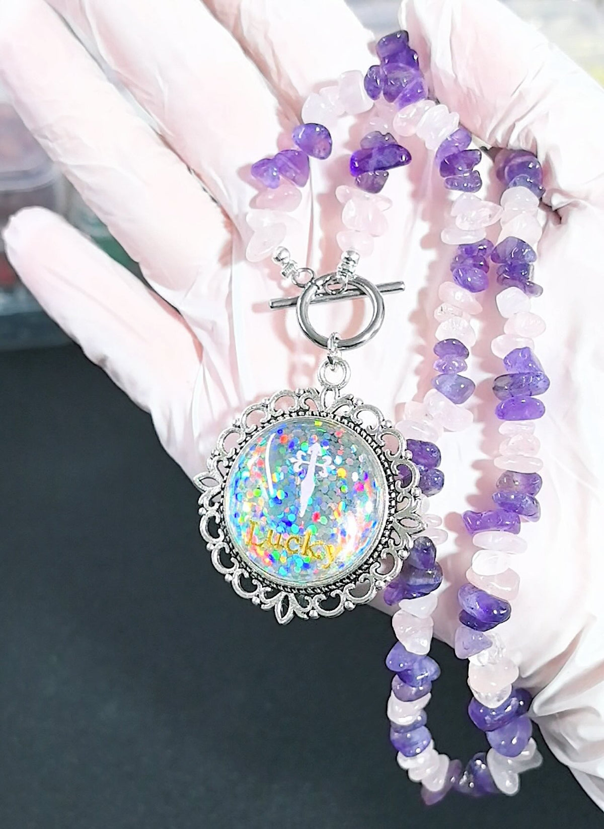 Close-up of a custom double-sided pet necklace showing the back of the vintage-style pendant, featuring sparkling glitter and a customized pet name.