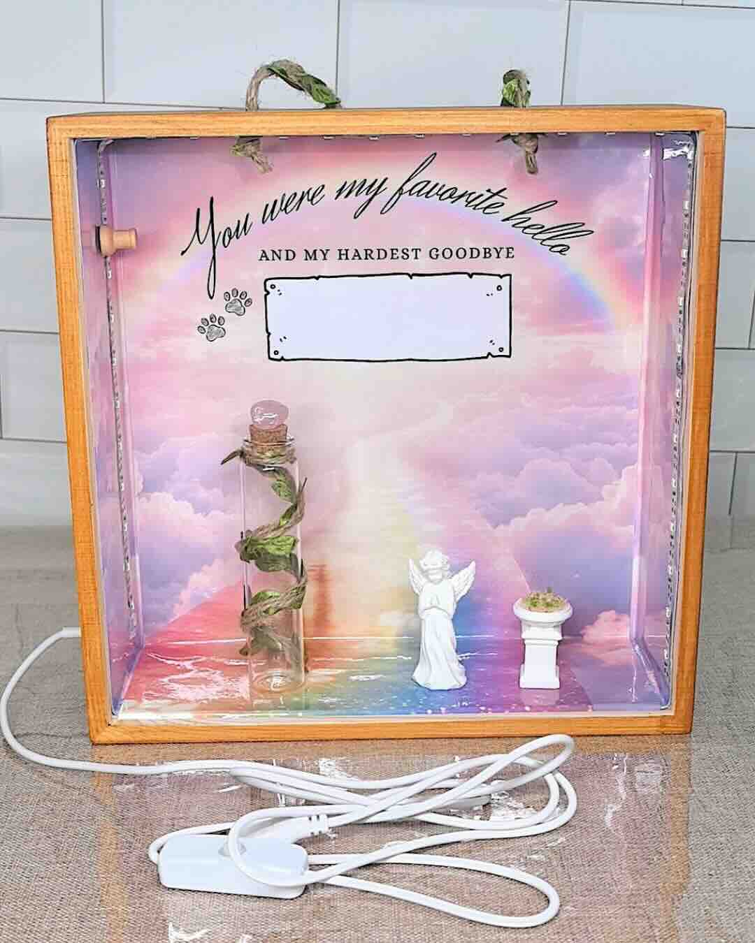 Blank template of the rainbow bridge pet memorial shadow box before personalization, showing the angel figurine, keepsake bottle, and light-up memorial scene.